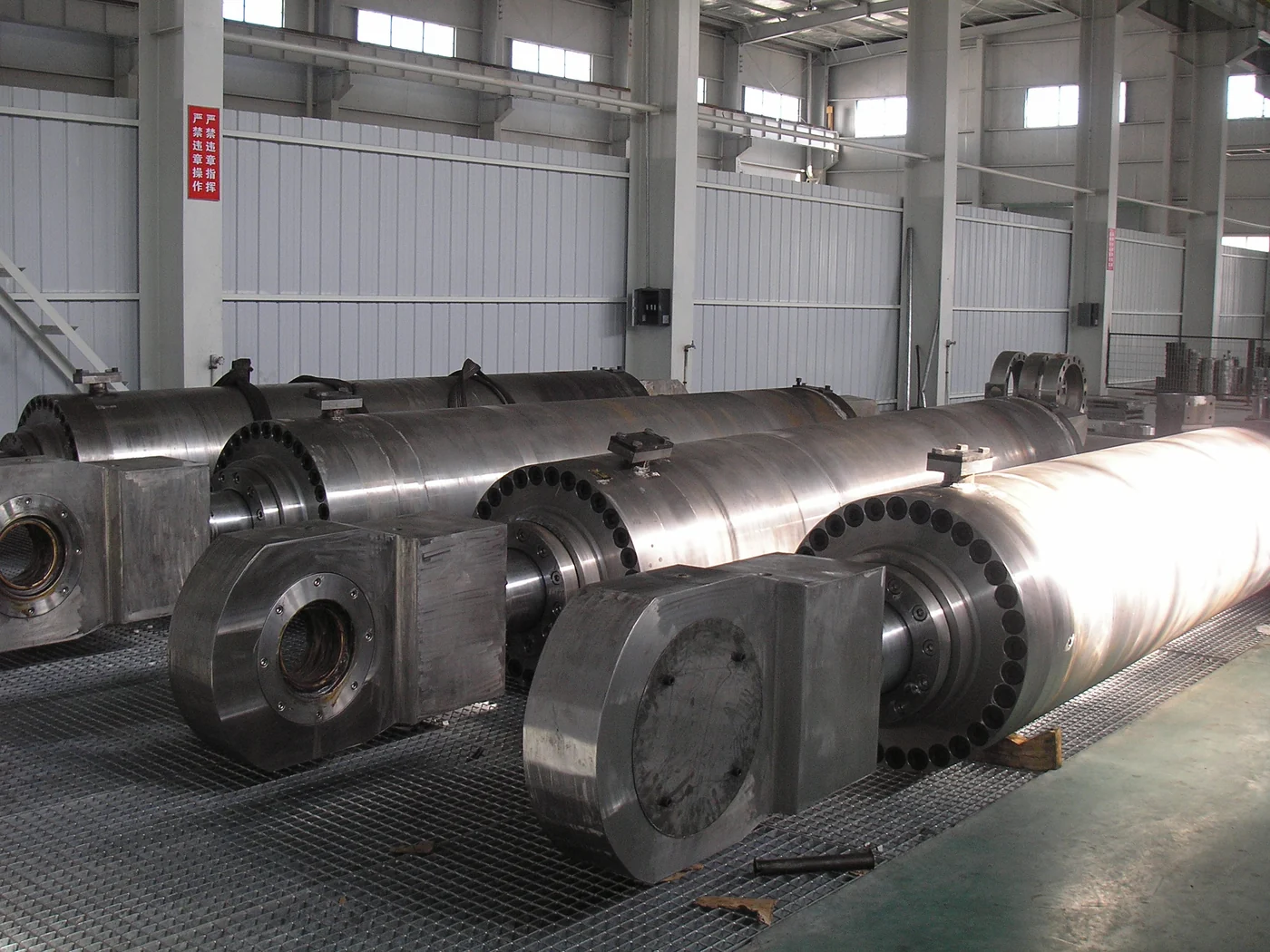 Large unpainted hydraulic cylinder assemblies with eye mounts in a workshop
