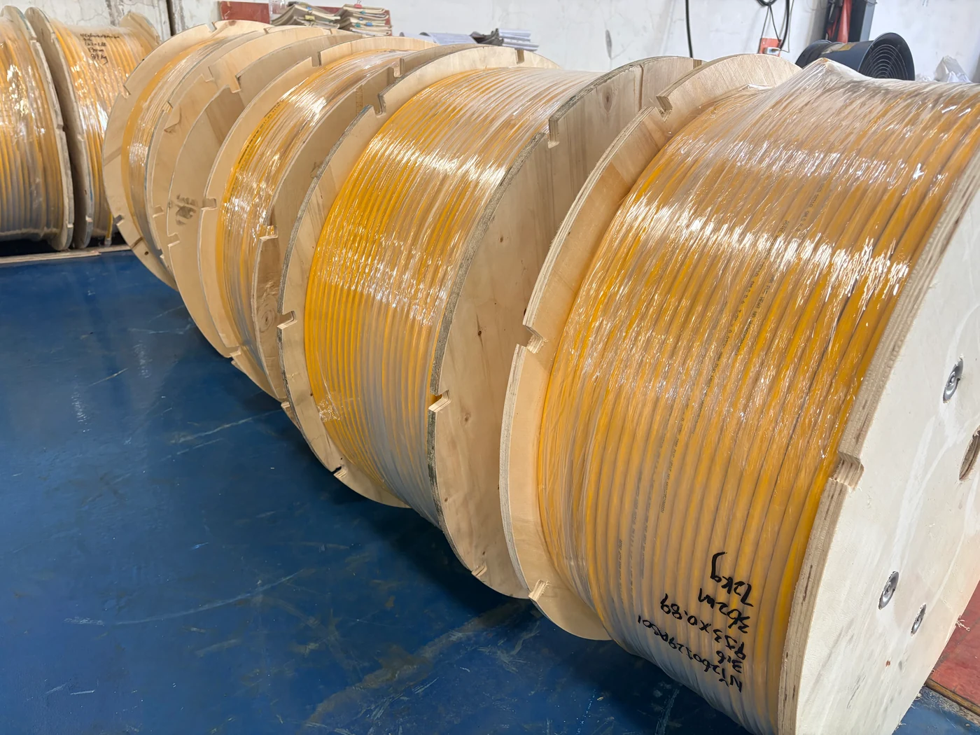 Yellow-jacketed tubing wound on wooden reels and covered with protective wrapping