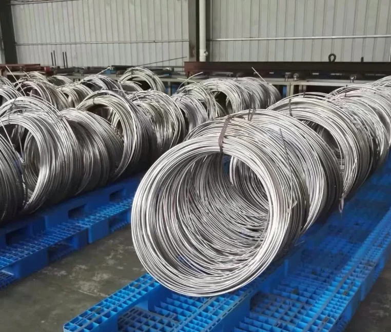 Rows of stainless steel tubing coils secured on blue pallets in a workshop