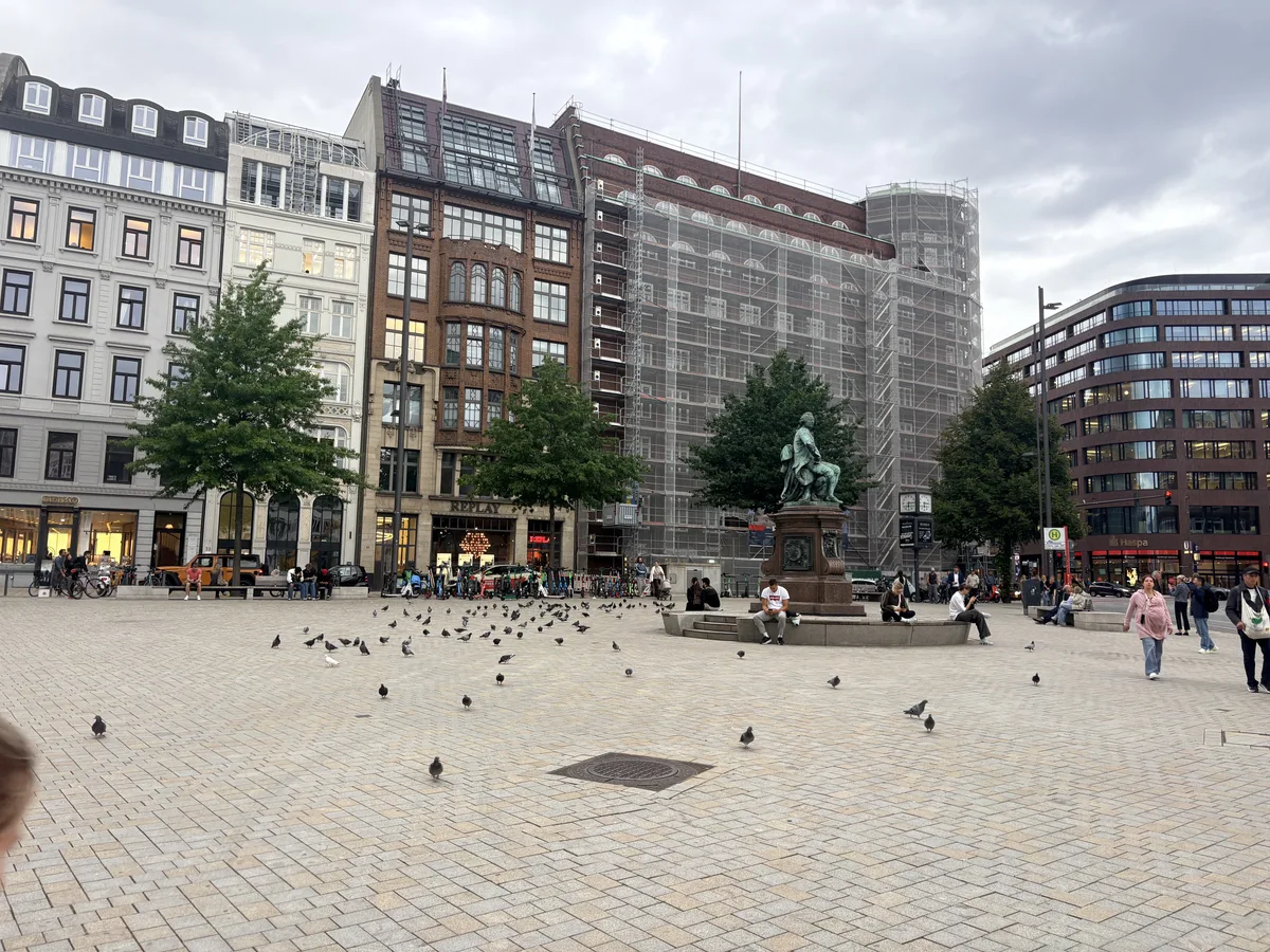 A public square in Hamburg with a statue and surrounding city buildings