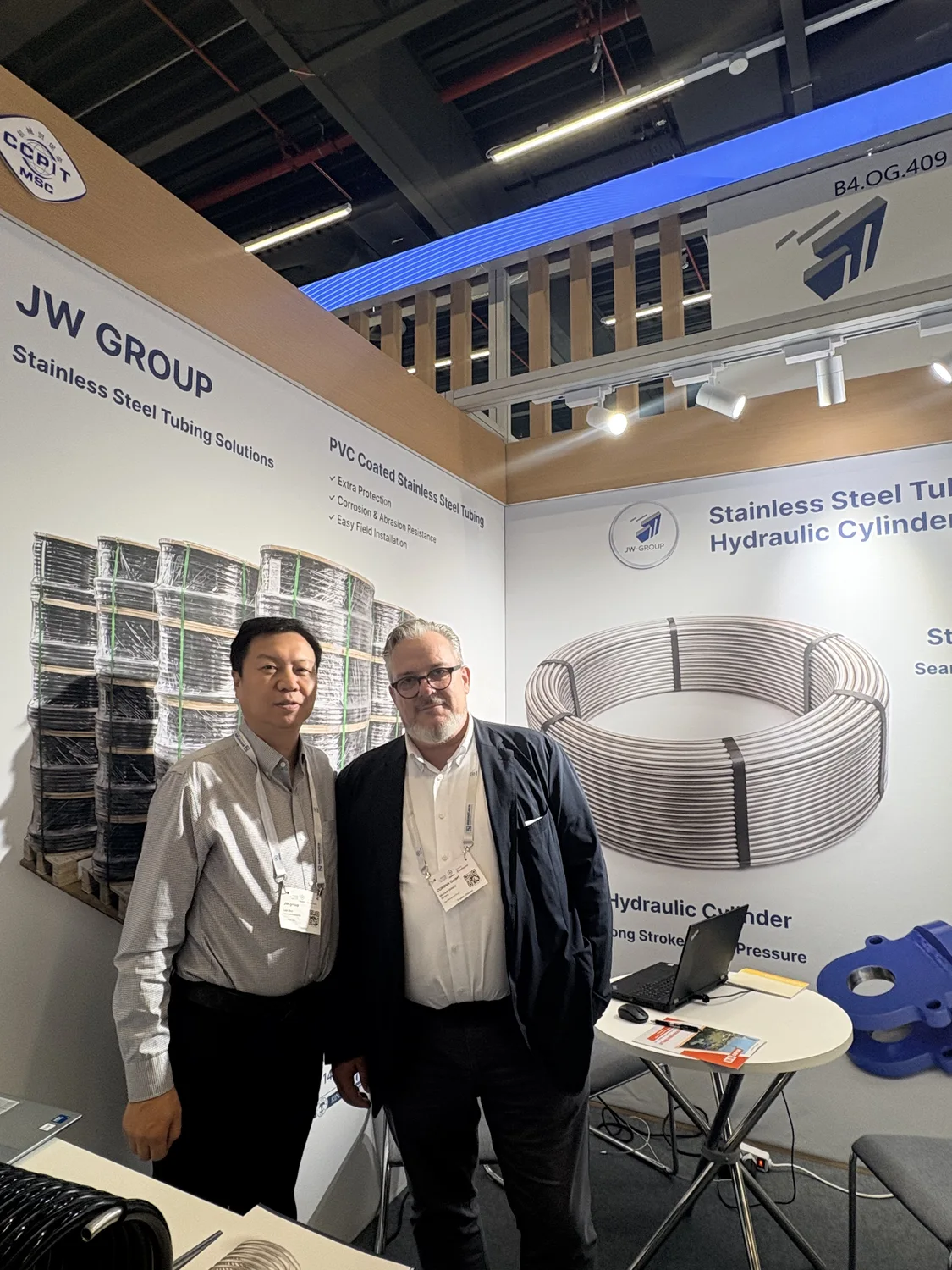 Two attendees pictured at JW-GROUP stand B4.OG.409 with cylinder and tubing displays