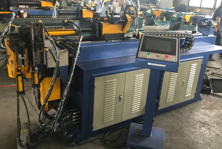Tube bending machine with workholding tools and a control panel in the workshop