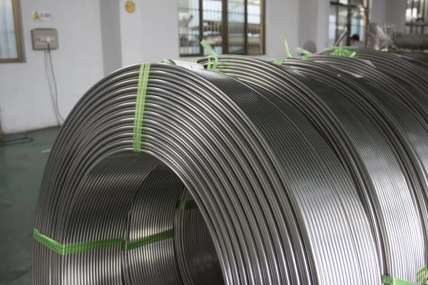 Large stainless steel tubing coils secured with green straps in a workshop